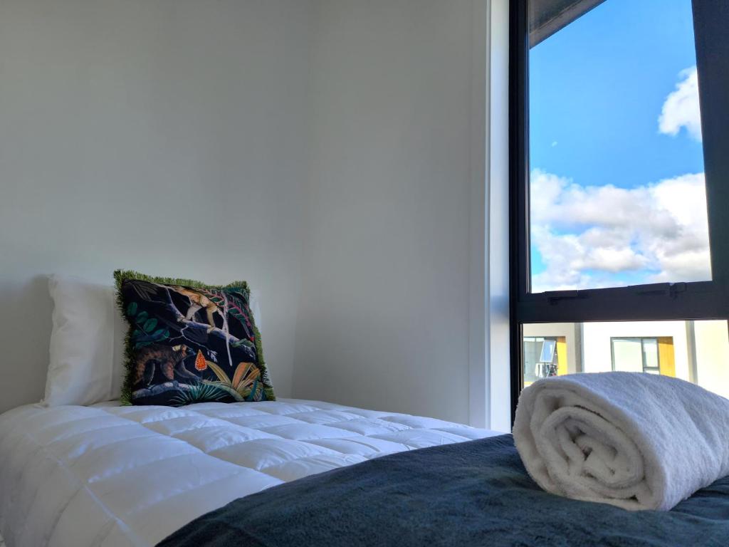 Una cama con una toalla en una habitación con ventana en U Suites on Trieste Way, en Paraparaumu