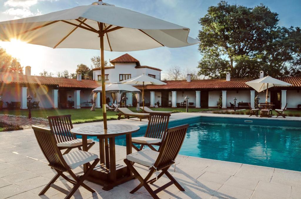 una mesa con sillas y una sombrilla junto a la piscina en Finca Las Margaritas en Chicoana