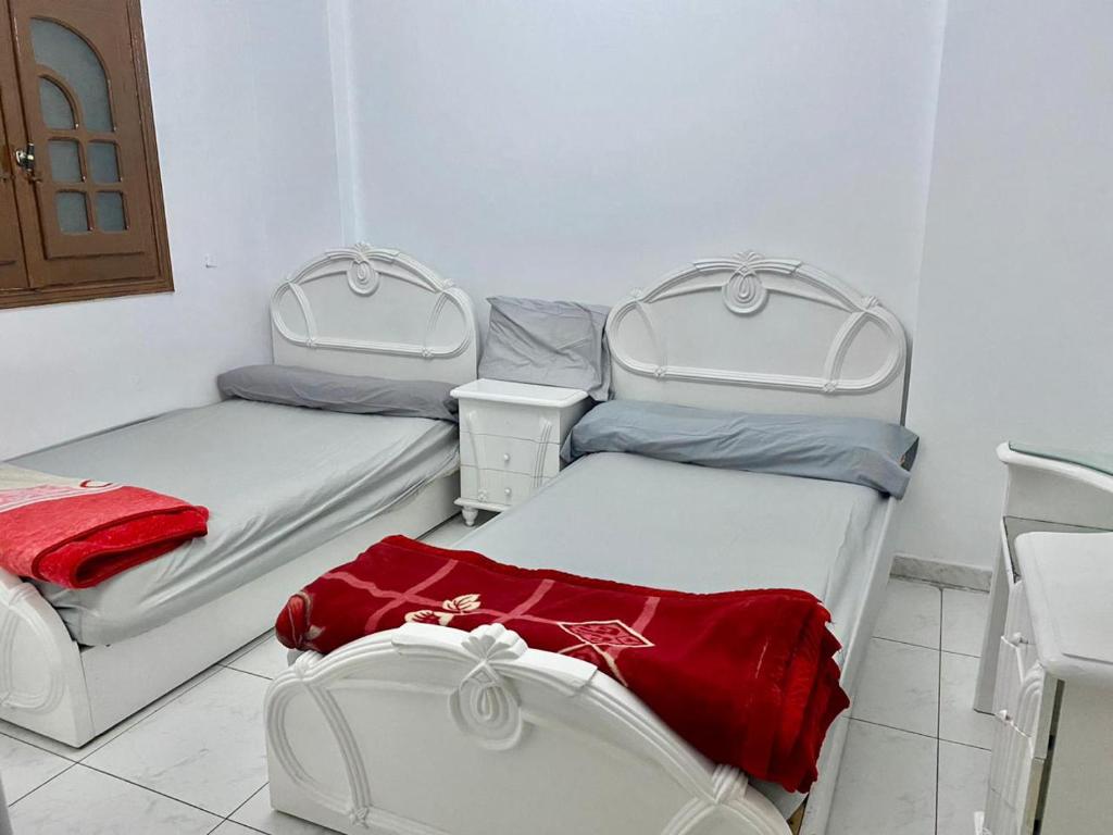 Cette chambre comprend 3 lits avec des draps rouges. dans l'établissement ميامي بير مسعود, à Alexandrie