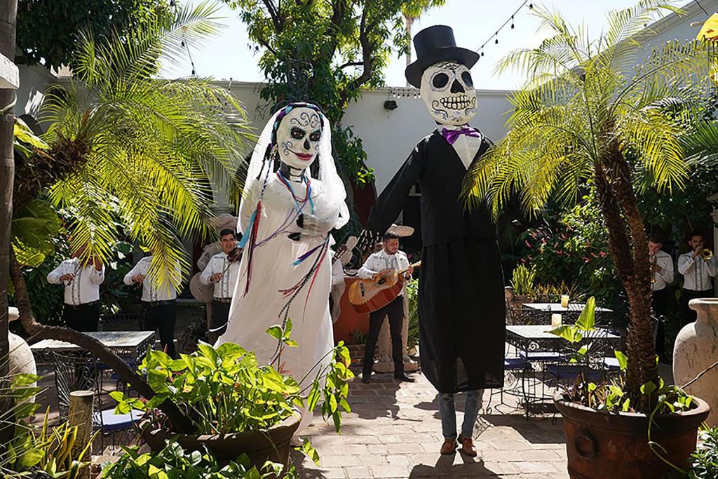 una pareja vestida de esqueleto de pie en un jardín en Hotel la Mansión, en Álamos