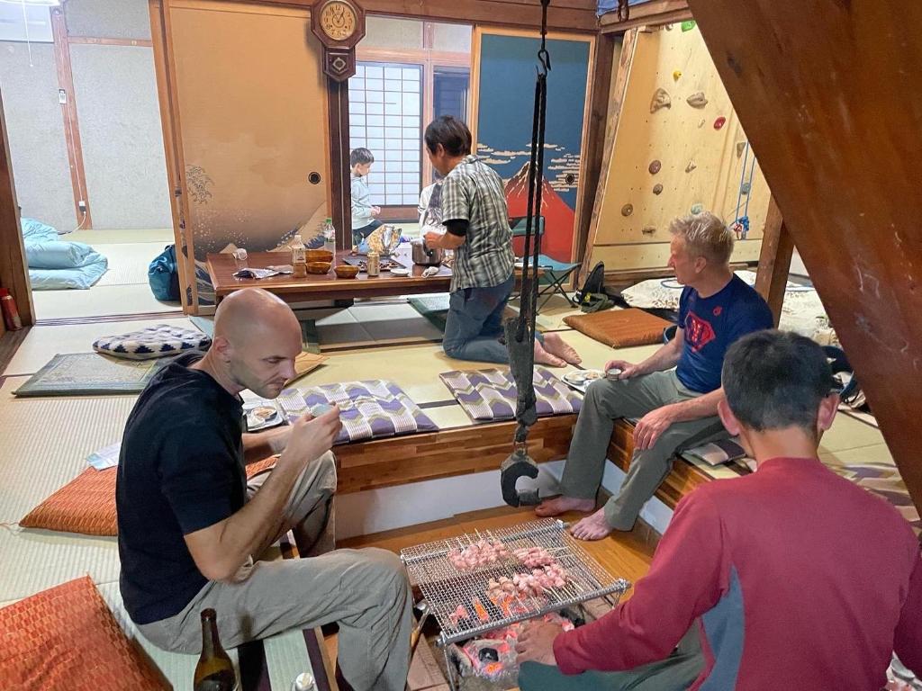 Eine Gruppe Männer, die auf dem Boden sitzen und ein Brettspiel spielen. in der Unterkunft ゲストハウス餓鬼大将 in Omachi