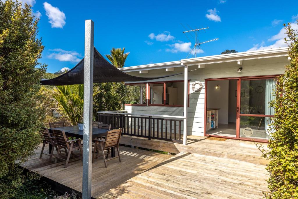a deck with a table and chairs on a house at Onetangi Beach Retreat - Waiheke Holiday Home in Onetangi