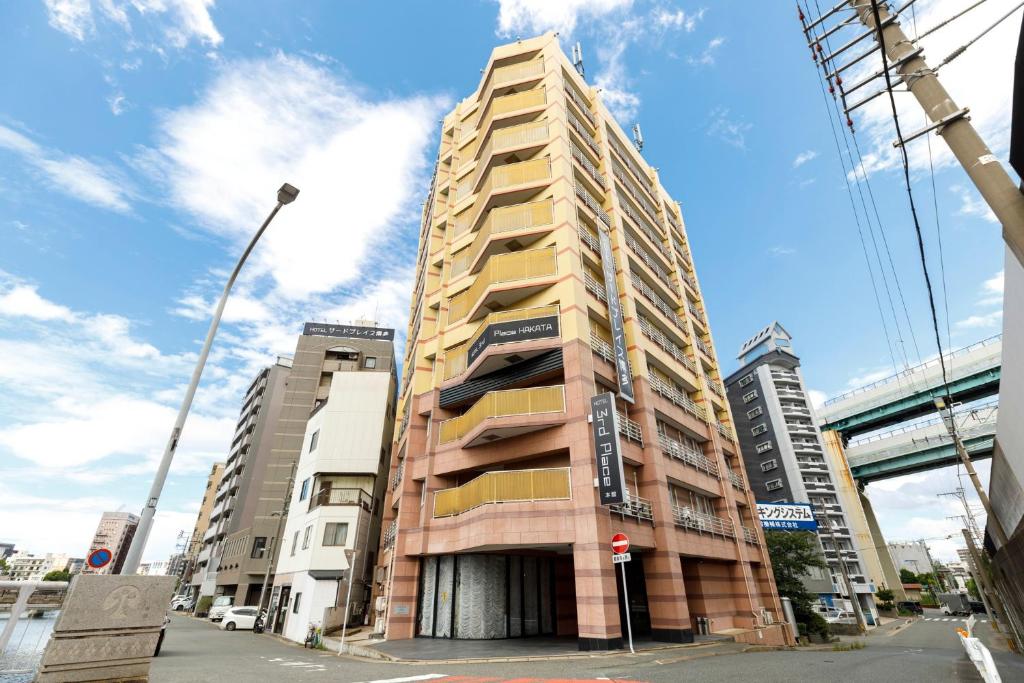 a tall building on a city street with buildings at HOTEL Third Place Hakata in Fukuoka