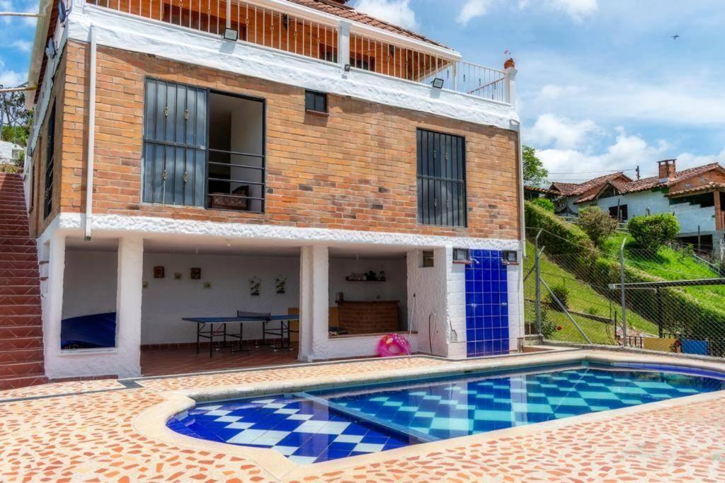 une villa avec une piscine en face d'une maison dans l'établissement Finca La Piscina, disfrute total, à Marinilla