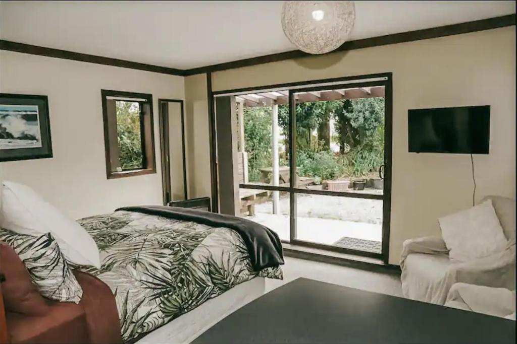 ein Schlafzimmer mit einem Bett, einem Sofa und einem Fenster in der Unterkunft Evergreen Escape Hokitika in Hokitika