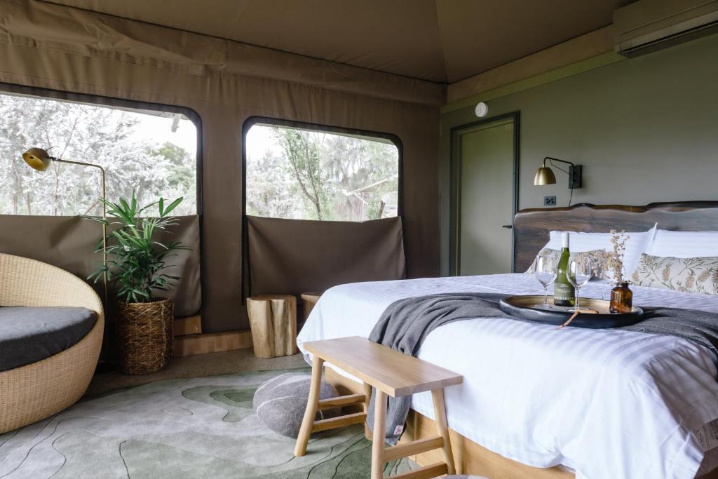 a bedroom with a bed and a chair and two windows at Peninsula Hot Springs in Fingal