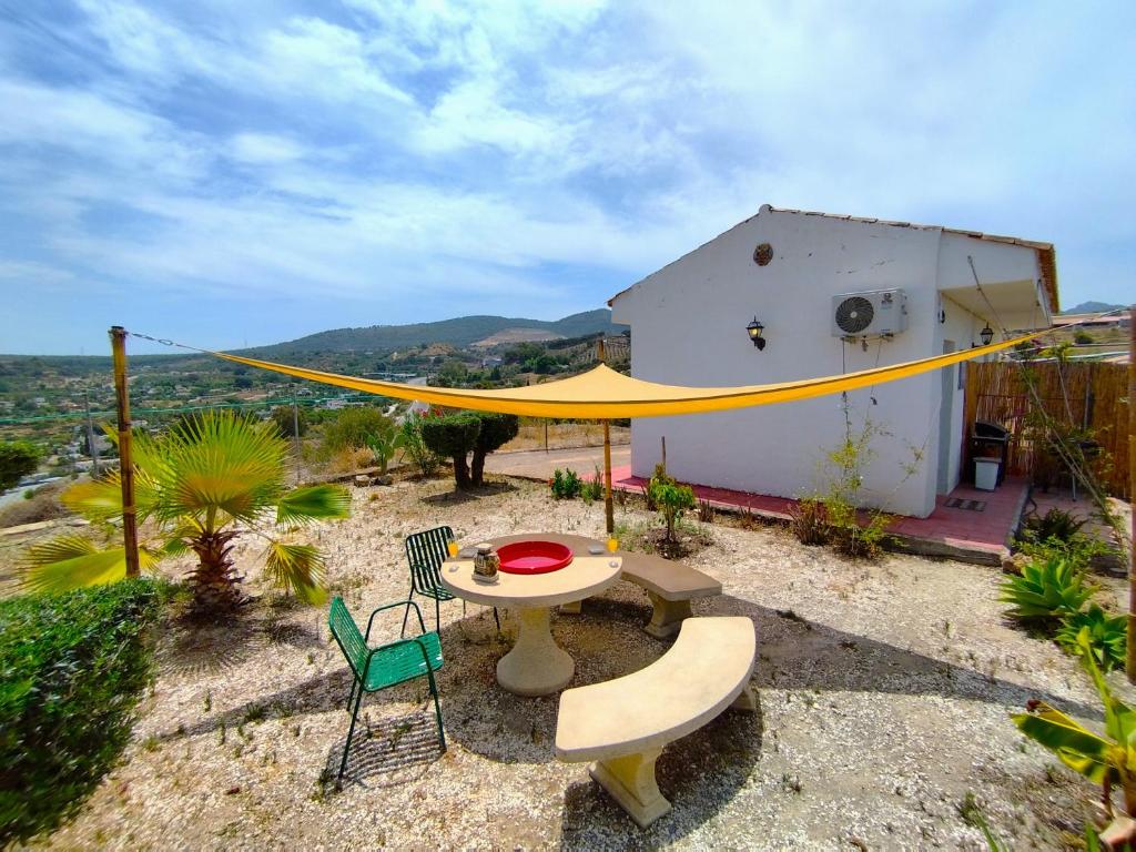 een patio met een tafel en stoelen en een geel net bij Casita rural de Tamara in Coín