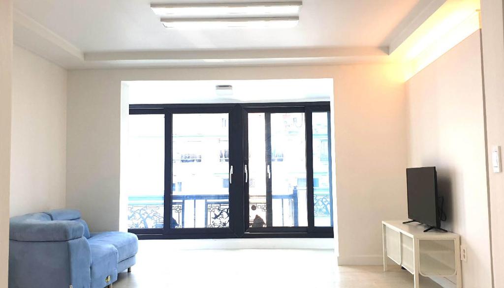 ein Wohnzimmer mit einem blauen Sofa und einem TV in der Unterkunft Elle House in Jeonju