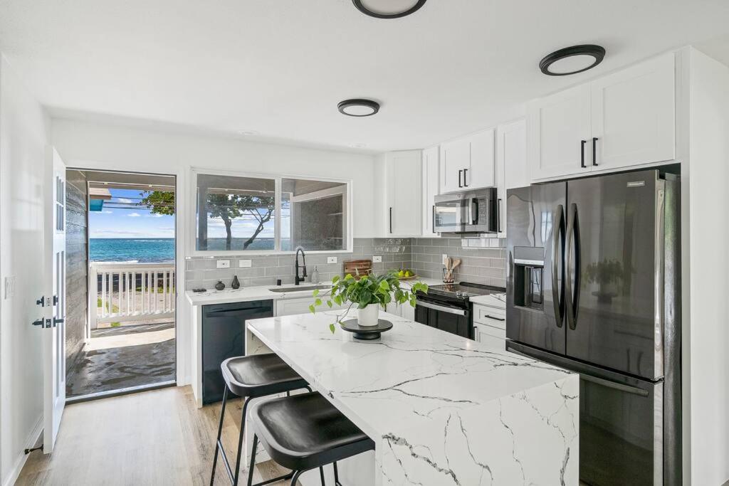 a white kitchen with a large marble counter top at Serenity by the Sea Ultimate Beachfront Escape in Hauula