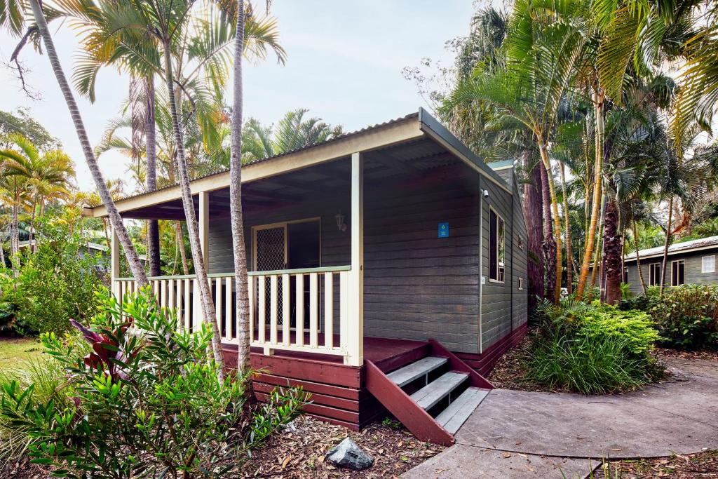 a small house with a porch and palm trees at NRMA Darlington Beach Holiday Resort in Arrawarra