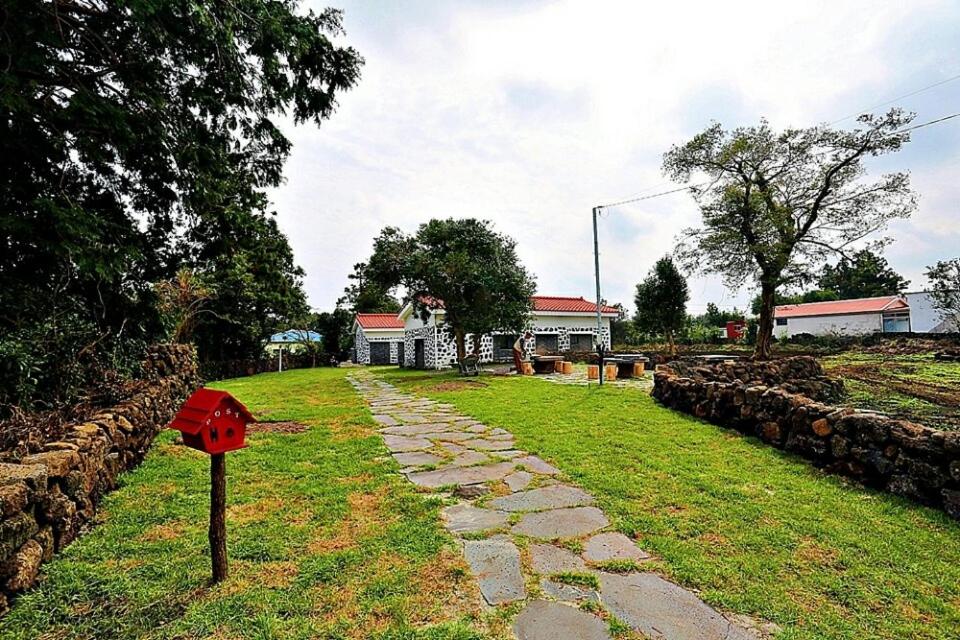 un camino de piedra frente a una casa con un buzón rojo en Onsaemiro, en Seogwipo