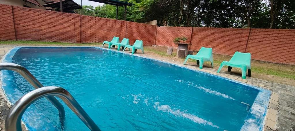 una piscina con sillas azules junto a una pared de ladrillo en Beatiful Afamosa Golf Resort Private villa with pool 3 rooms lot 1280 bumiputra only, en Kampong Alor Gajah