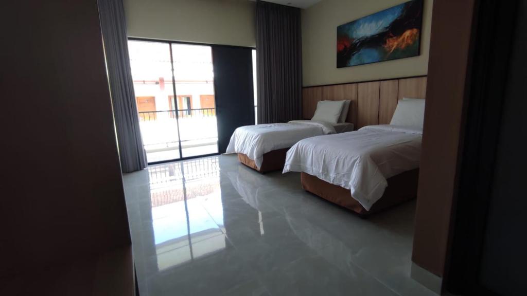 a bedroom with two beds and a balcony at Rabasta Enjoy Kuta in Denpasar
