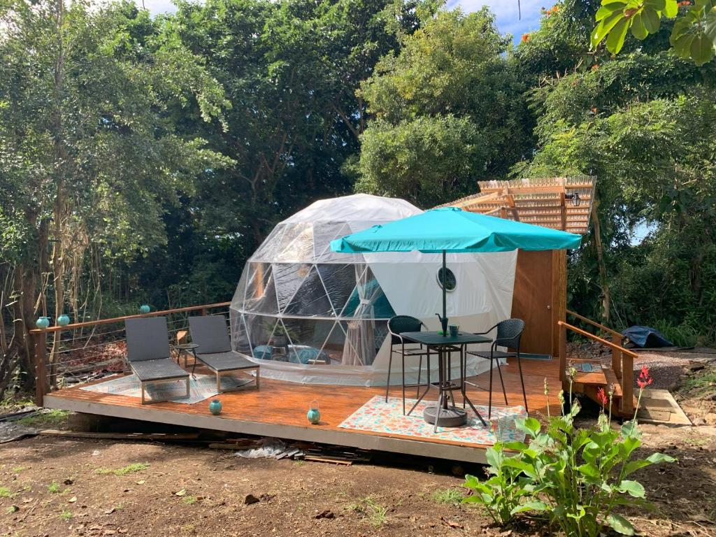 Jurte mit einem Tisch, Stühlen und einem Sonnenschirm in der Unterkunft Manta Soul Jungle Geodome in Kealakekua