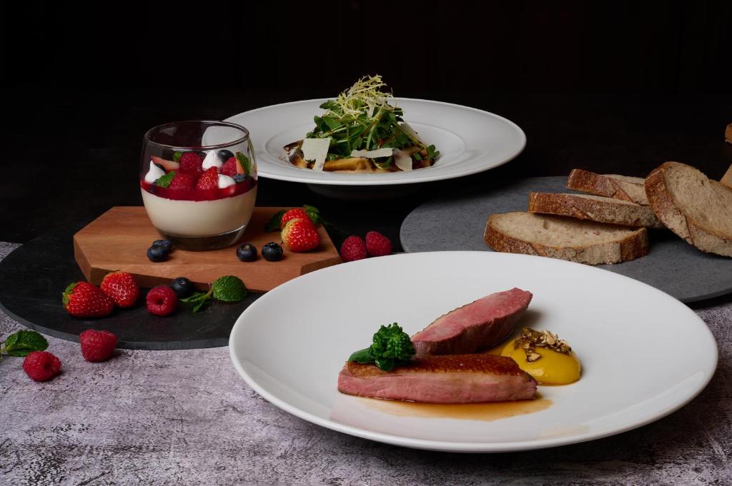 two plates of food on a table with bread and strawberries at Sheraton Grande Sukhumvit, a Luxury Collection Hotel, Bangkok in Bangkok