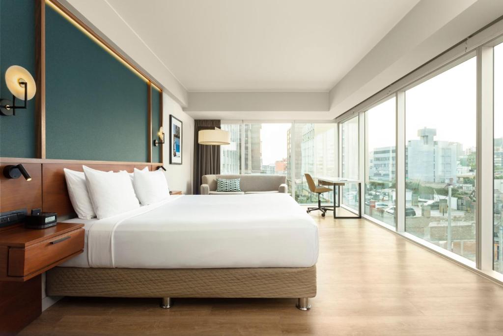 a bedroom with a large bed and a large window at Courtyard by Marriott Lima Miraflores in Lima