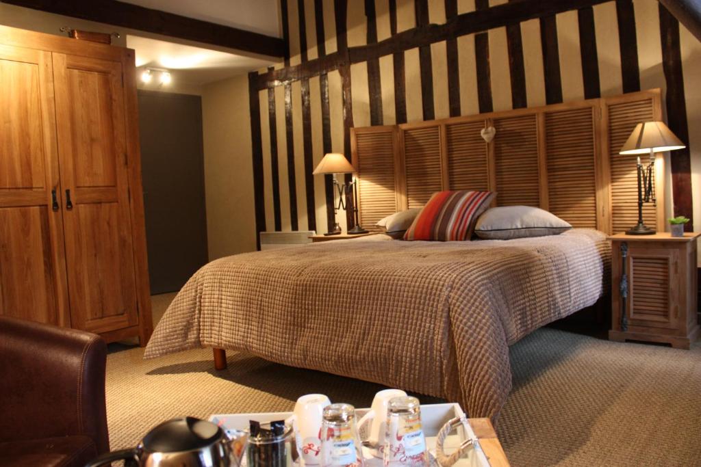 Schlafzimmer mit einem großen Bett mit einem Kopfteil aus Holz in der Unterkunft Les Songes d'Héléna in Honfleur