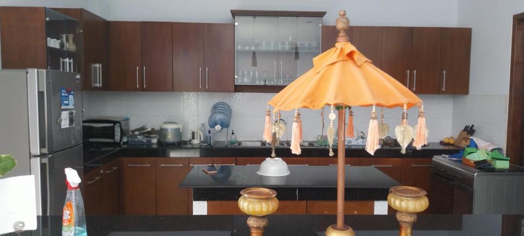 a kitchen with a table with an umbrella in it at Kelana Guest House manage by LBV in Jimbaran