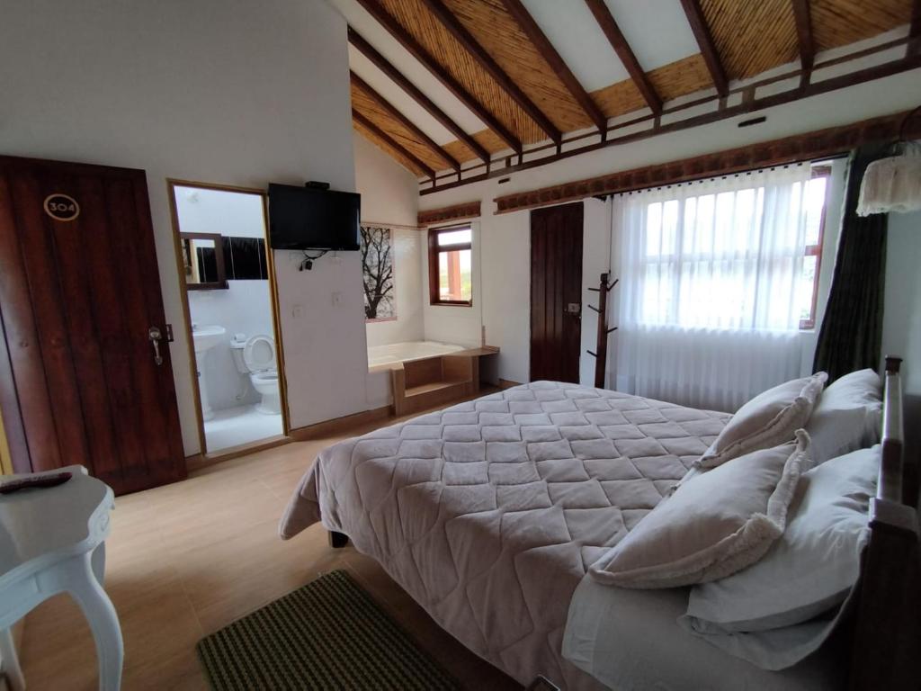 um quarto com uma cama grande e uma casa de banho em Hotel Artemisa em Sutamarchán