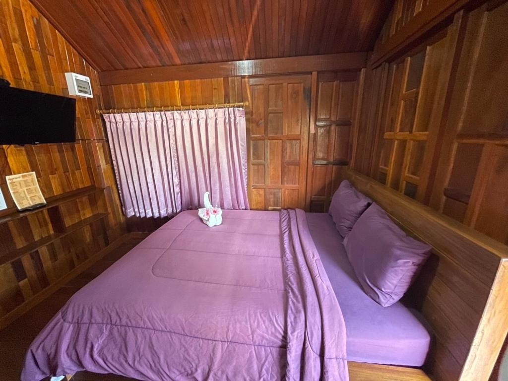 a small bed in a wooden cabin with purple sheets at The Best Garden resort in Sichon