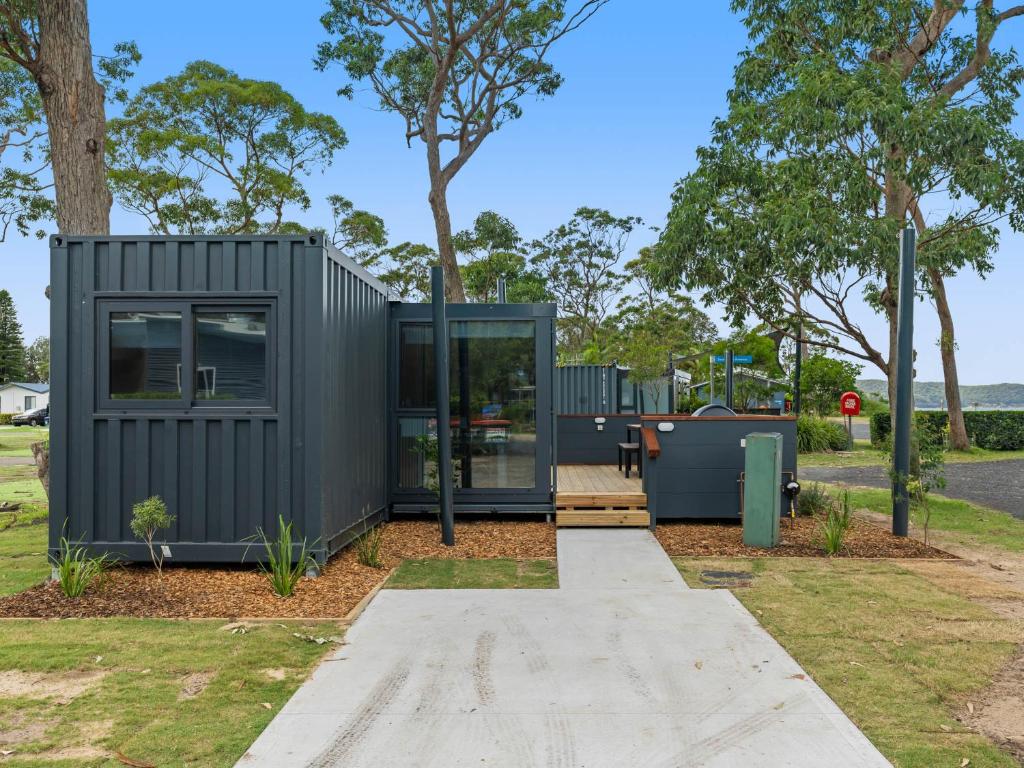 a black tiny house sitting in a park at NRMA Ocean Beach Holiday Resort in Umina