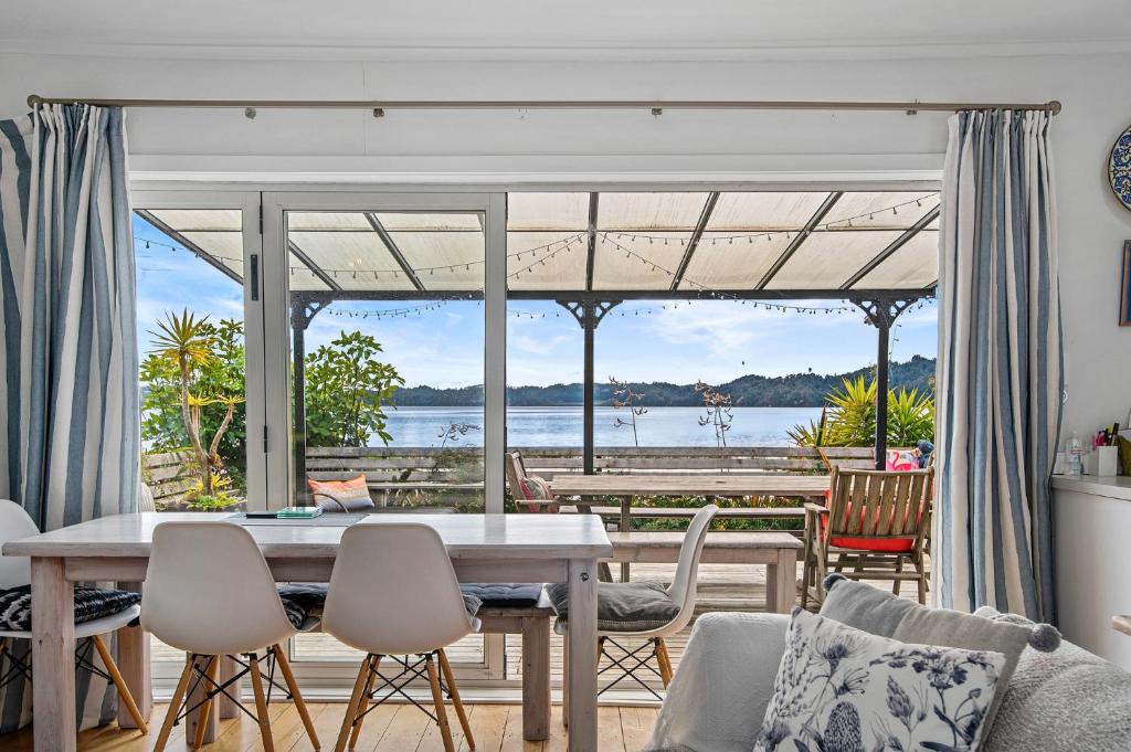 uma sala de jantar com vista para a água em Lakefront Treasure - Lakefront Rotomā Holiday Home em Rotorua
