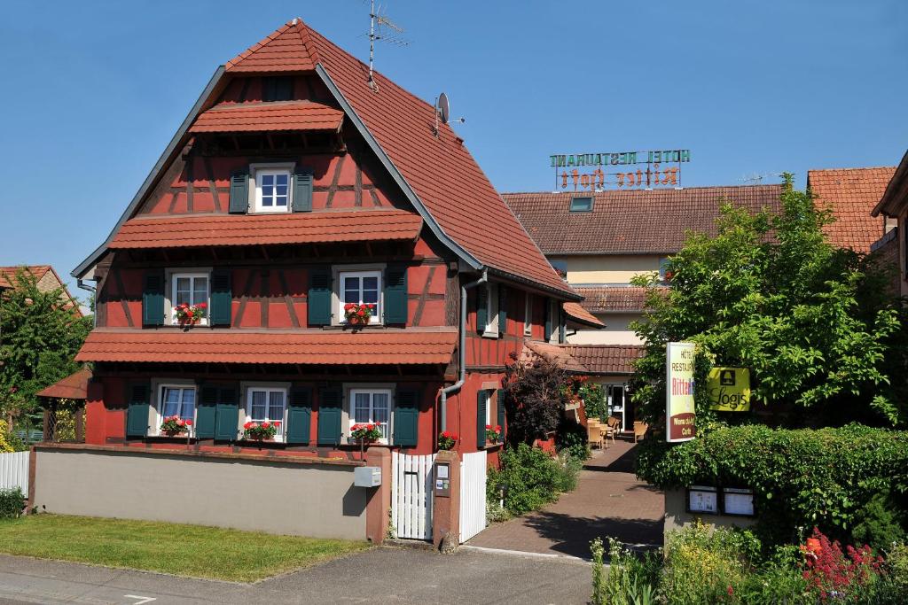 una casa con tetto rosso e fiori alle finestre di Hôtel Restaurant Ritter'hoft a Morsbronn-les-Bains