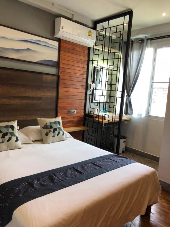 A double room with a wood-paneled feature wall, air conditioner and screened vanity area.