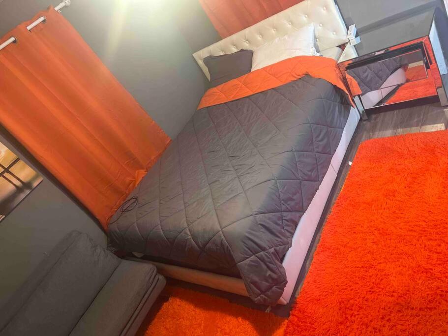 a bedroom with a bed with an orange blanket at Backyard Guesthouse in Miami Gardens