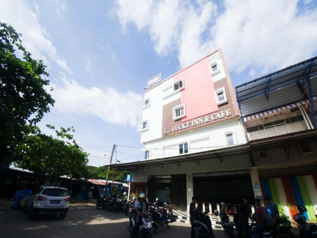 een roze gebouw met motoren geparkeerd voor het bij Lucky Inn & Cafe in Patjinongong