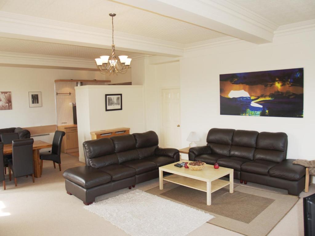 a living room with black leather furniture and a table at Royal Mile Mansions Apartment Edinburgh in Edinburgh