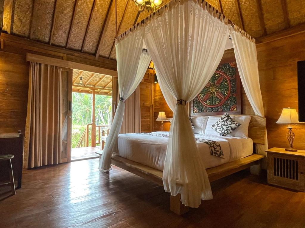 ein Schlafzimmer mit einem Himmelbett in der Unterkunft Sirya Farm House in Meliling