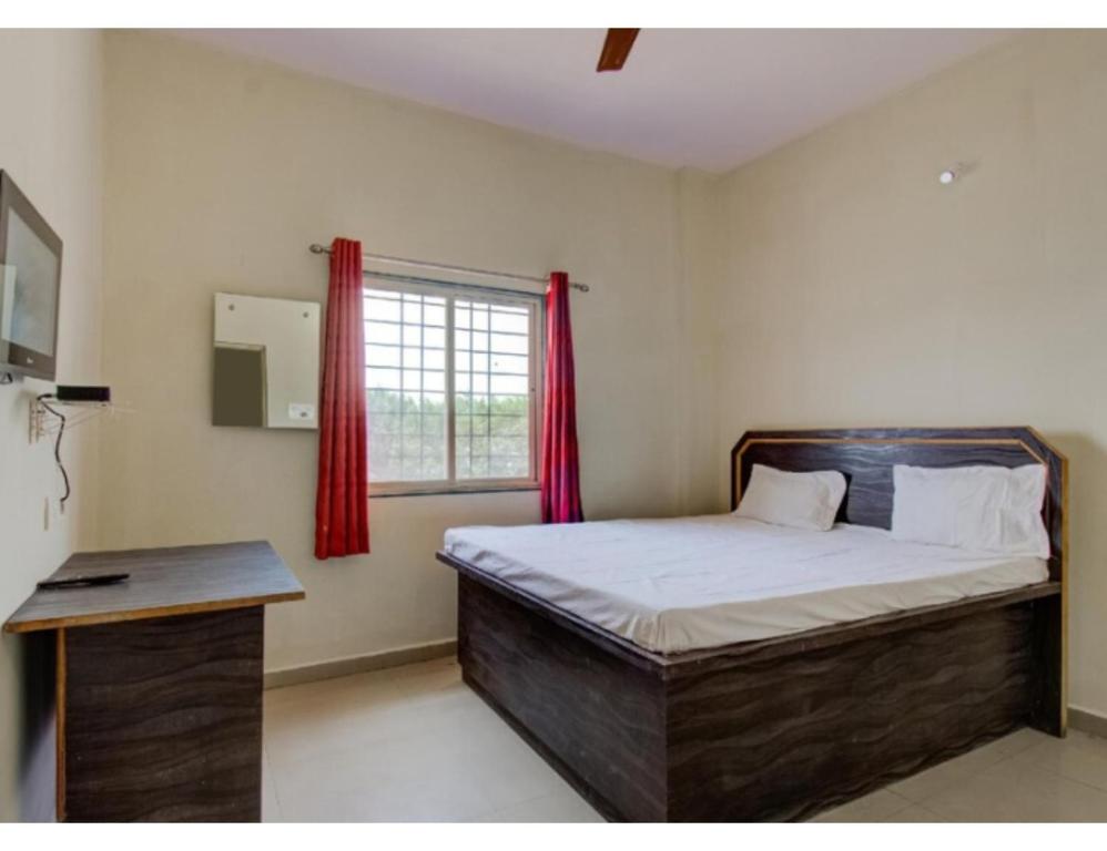 Vedanta Hotel, Bareilly في بريلي: غرفة نوم بسرير ونافذة ذات ستائر حمراء