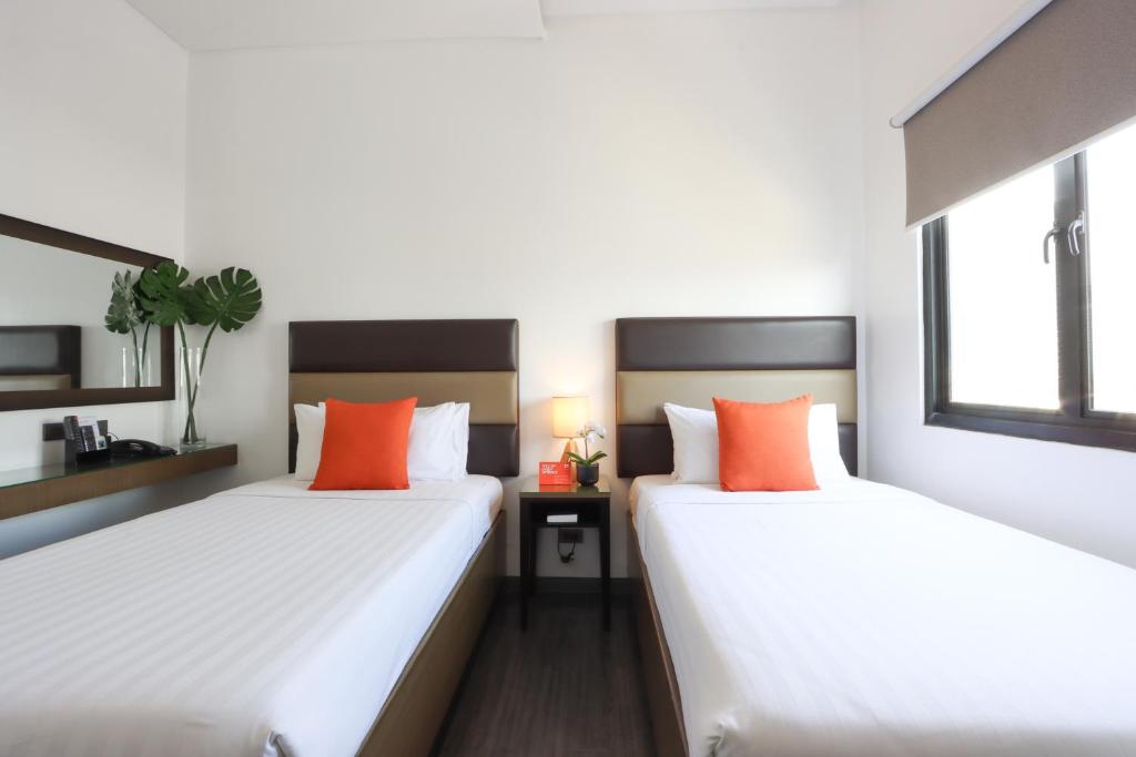 2 bedden in een kamer met witte en oranje kussens bij Privato Makati in Manilla