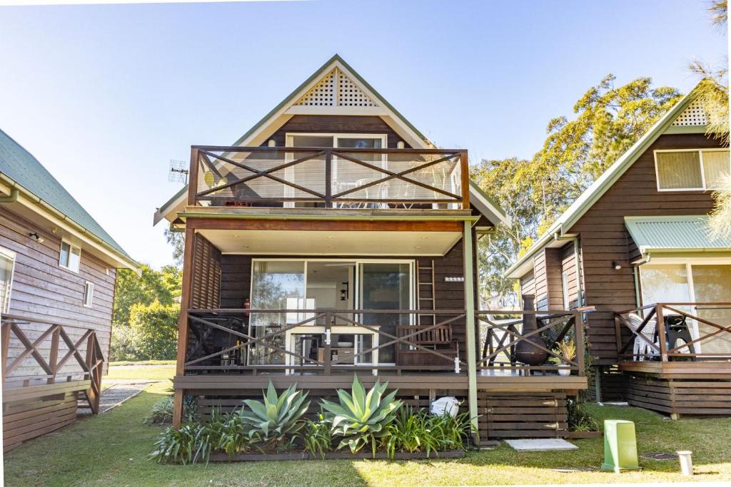 a house with a large deck with a balcony at Coral Cottage in Berrara