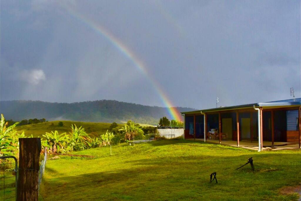 a rainbow in the sky over a house with a yard at Hilltop Retreat - best of both worlds: Beach/farm in Pillar Valley