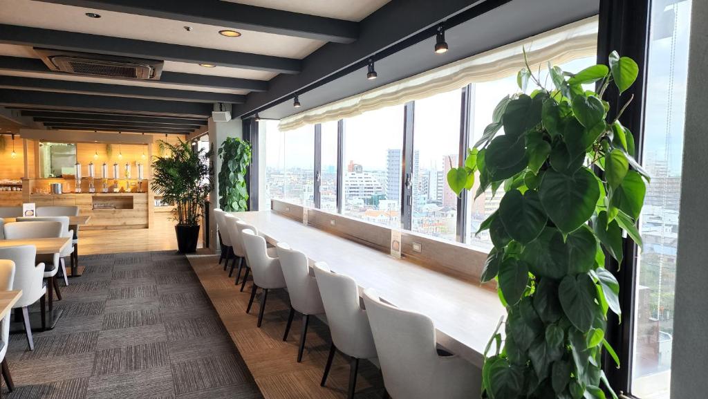 un ristorante con sedie bianche e una grande finestra di Platon Hotel Yokkaichi a Yokkaichi