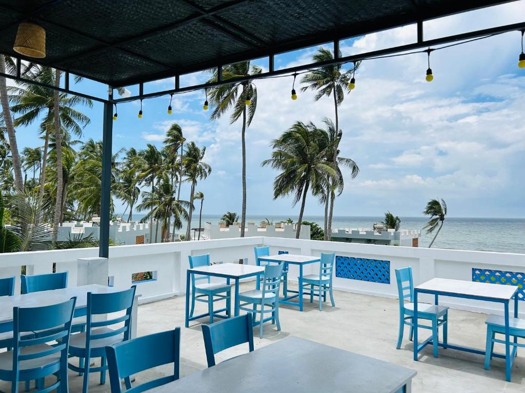 un patio con mesas y sillas y el océano en I Hostel Muine - A Little White Homestay By The Sea en Ấp Thiện Long