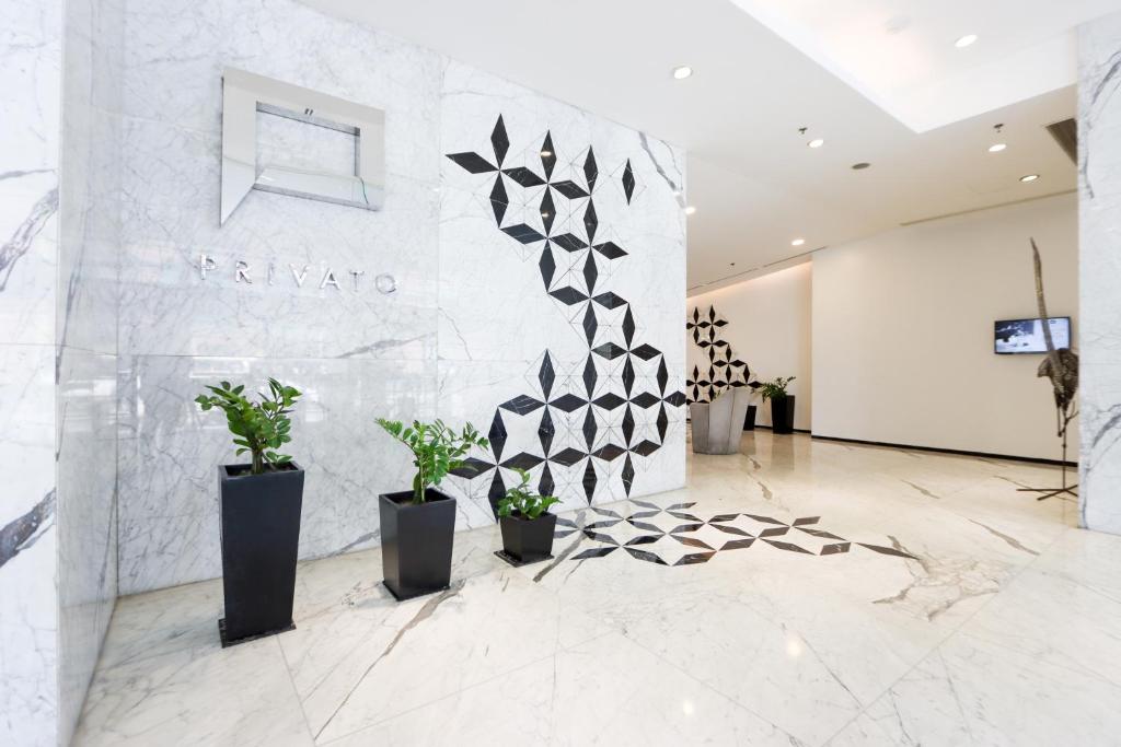 eine Lobby mit Topfpflanzen und einer Wand in der Unterkunft Privato Ortigas in Manila
