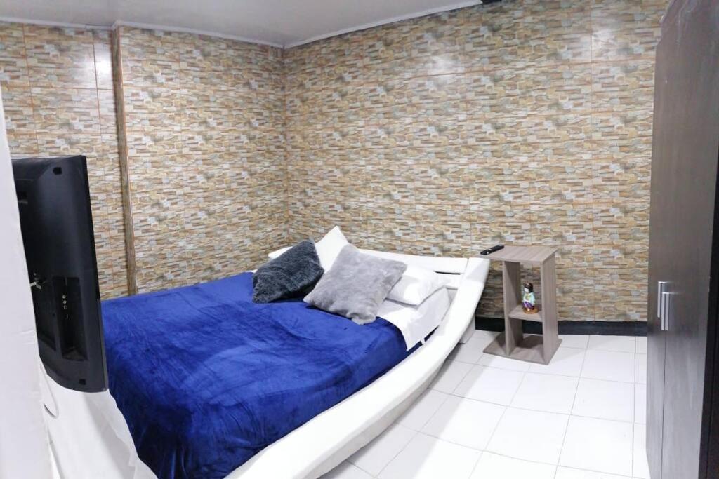 - une chambre avec un lit doté d'une couverture bleue et d'une télévision dans l'établissement Disfruta tu estancia en Pereira!, à Pereira