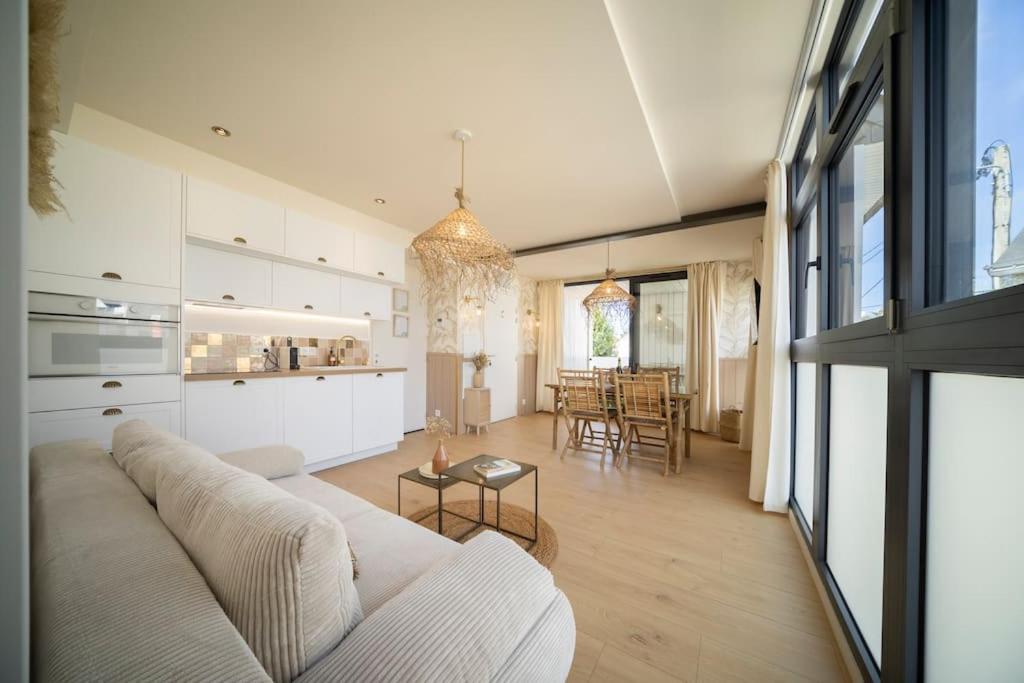 een woonkamer met een witte bank en een keuken bij Les Voiles - Appart'hotel "Le Kornog" in Carnac