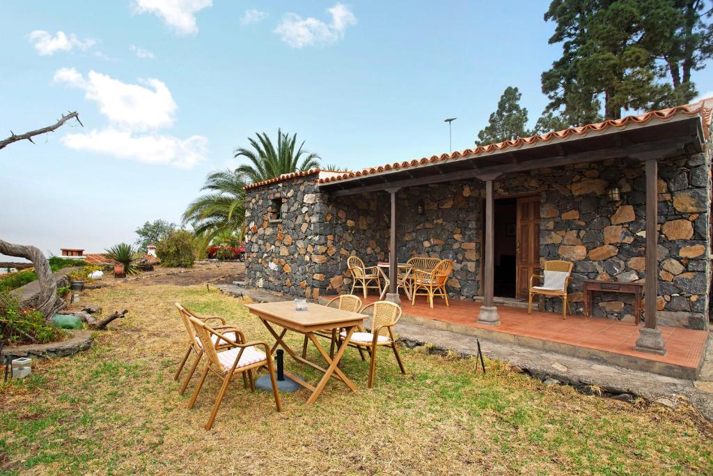 a stone house with a table and chairs in the yard at La Roquina in Tijarafe