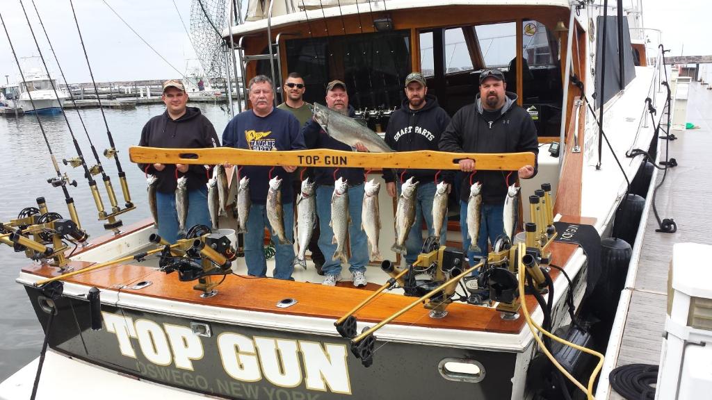 un grupo de hombres de pie en un barco con un pez en K&G Lodge, en Oswego