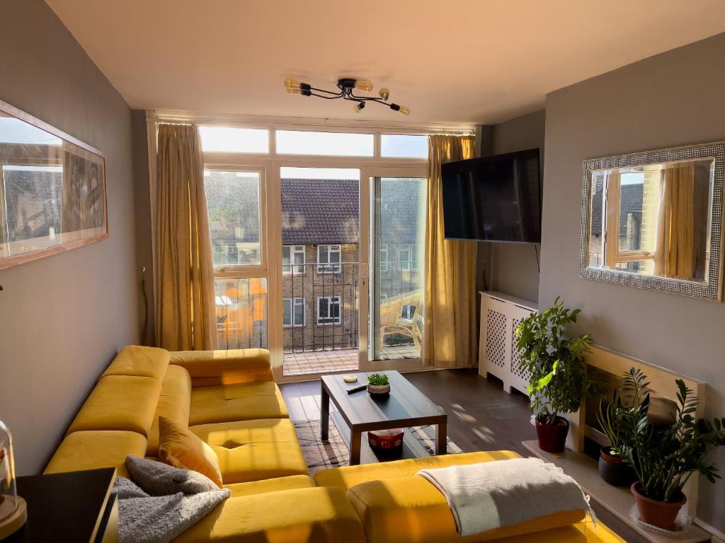 a living room with yellow furniture and a large window at Beautiful 3-bed apartment at Swiss Cottage in London