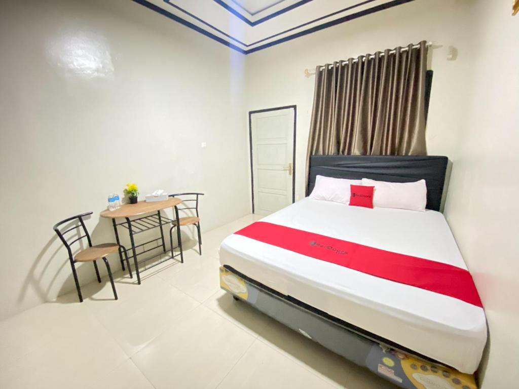 Un dormitorio con una cama y una mesa dentro. en RedDoorz @ Porodisa Homestay Palu, en Palu