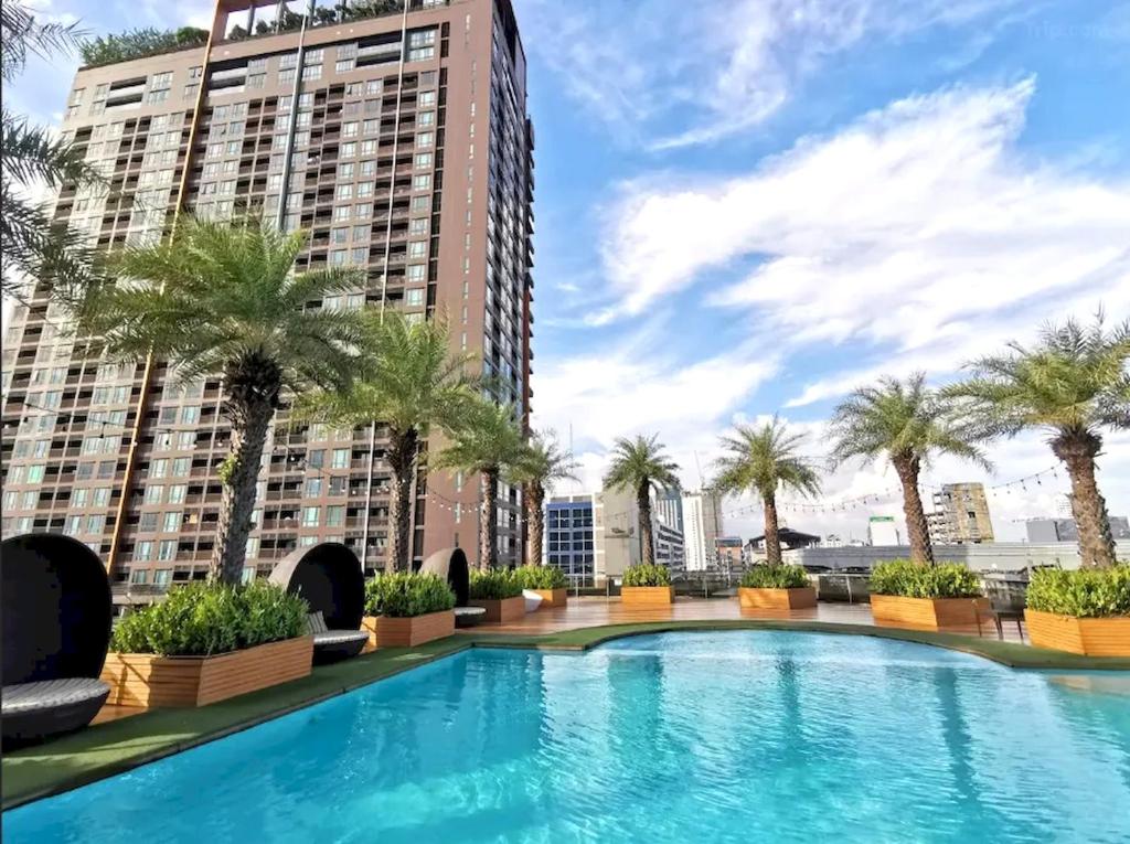 - une piscine sur le toit d'un immeuble avec des palmiers dans l'établissement Capital O 75451 Podstel Hostel Bangkok, à Bangkok