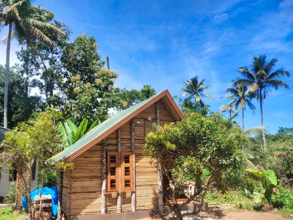 a small wooden house with palm trees in the background at Johns wooden cottages in Sultan Bathery