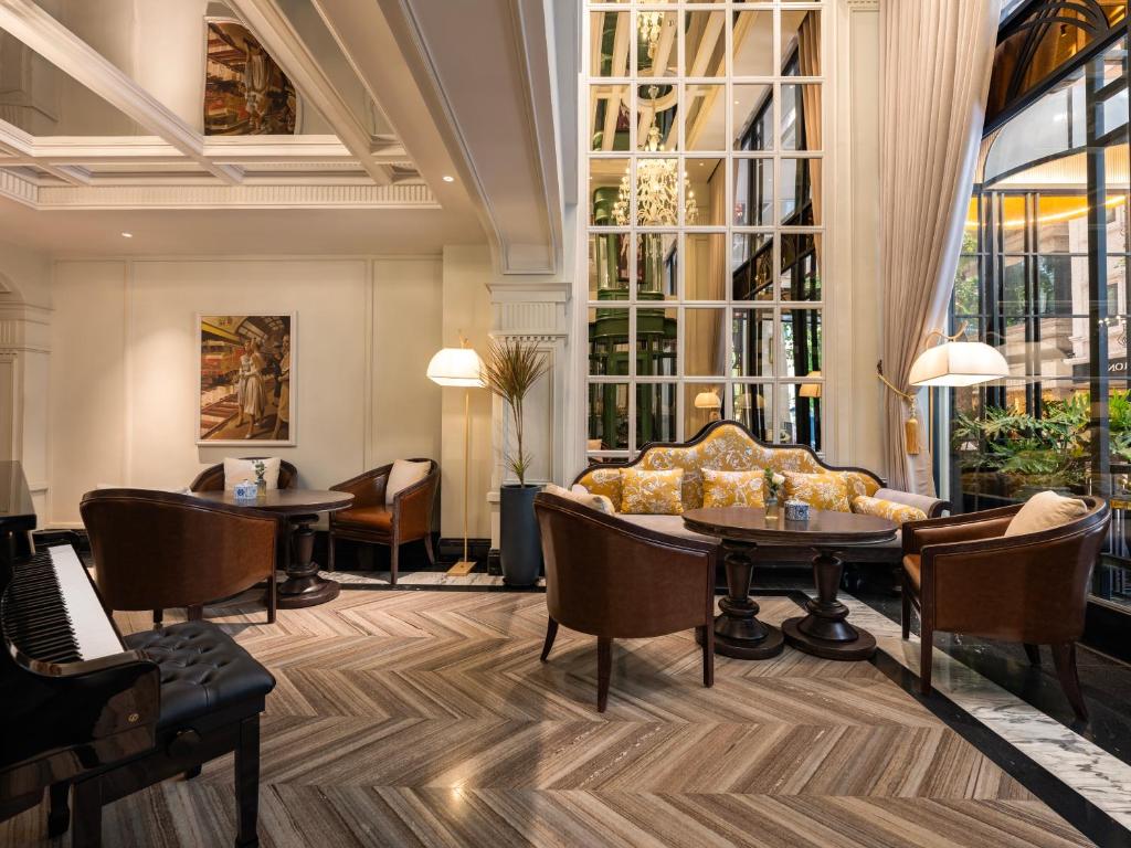a lobby with a couch and tables and windows at GRAND HOTEL du LAC Hanoi in Hanoi