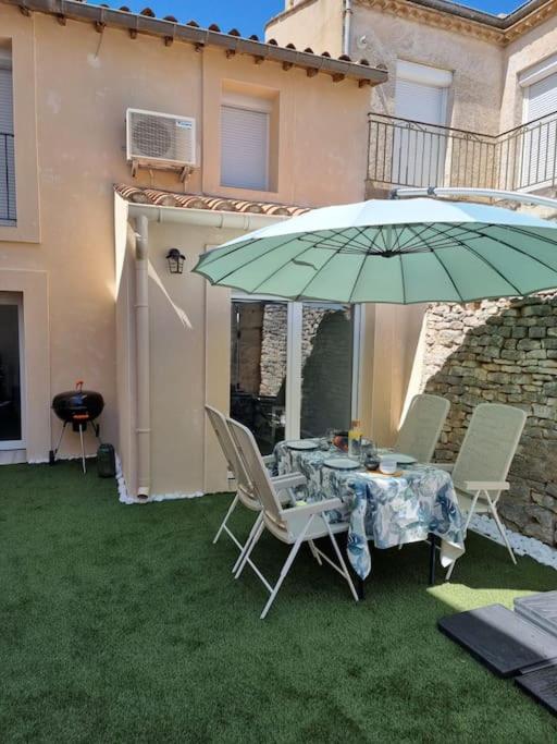 - une table et des chaises sous un parasol dans la cour dans l'établissement Charmante petite maison, à Le Crès