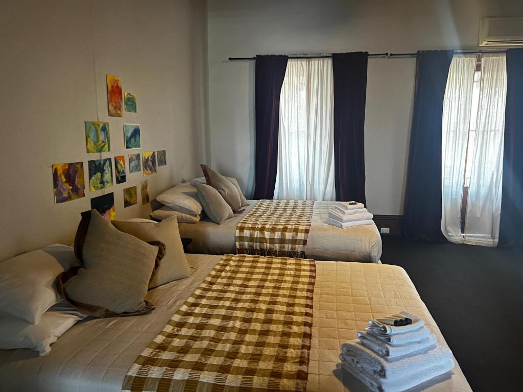 2 camas en una habitación con paredes y ventanas azules en The Family Hotel, en Maitland
